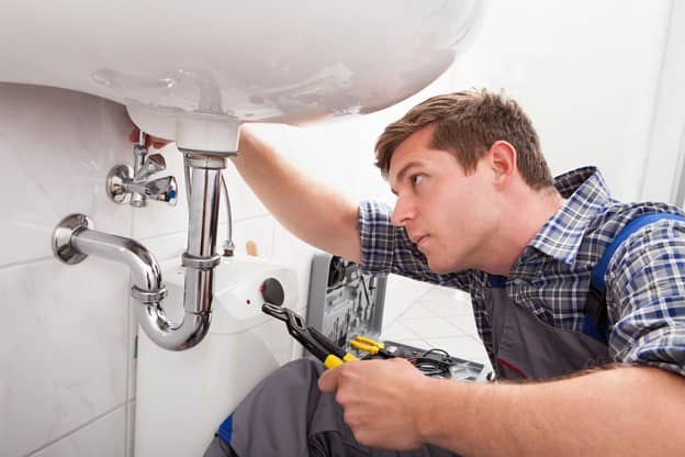 Man plumber in fixing sink in the bathroom